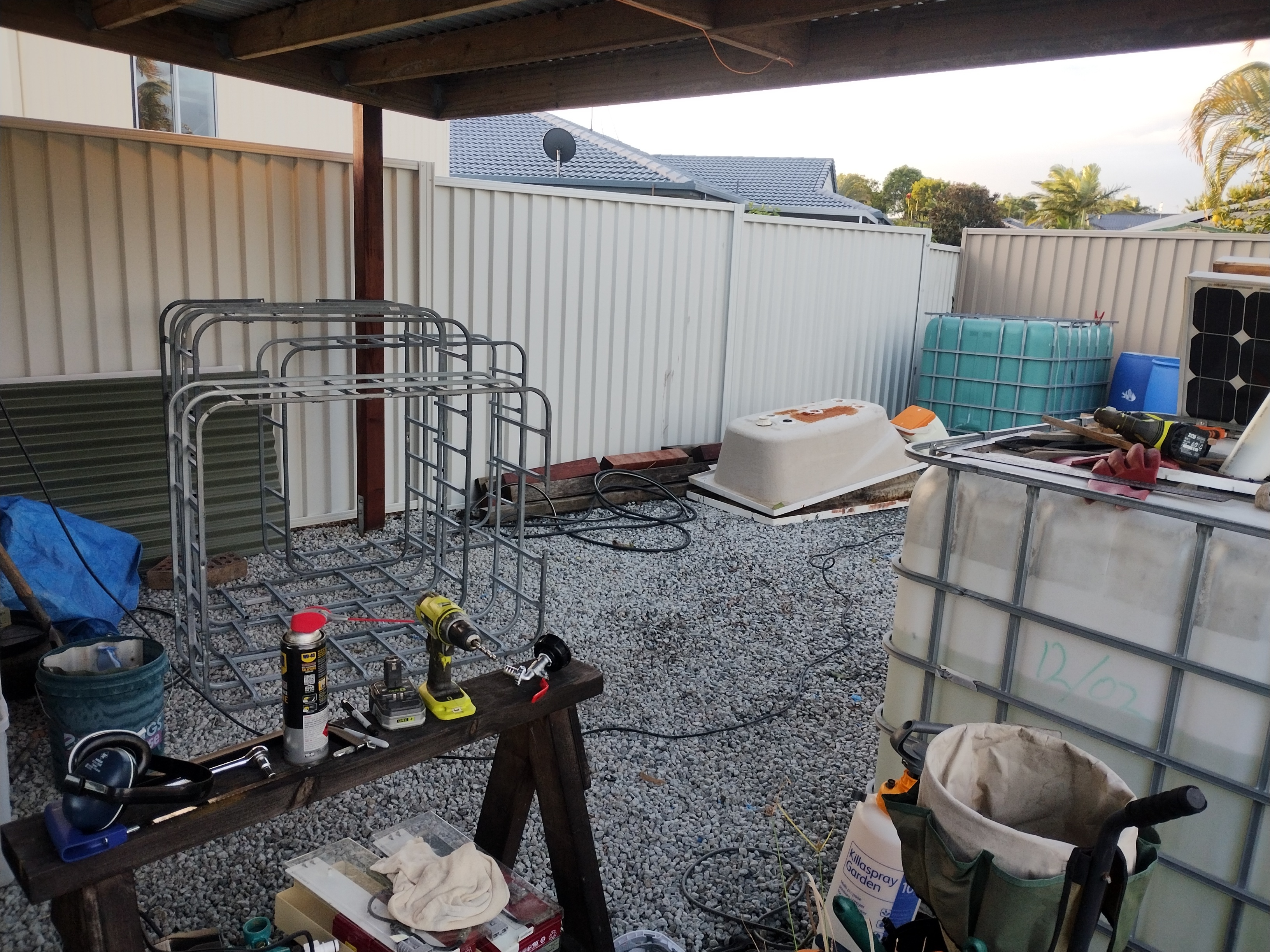 Freshly completed shanty: timber frame, IBC tanks, gravel floor, tools scattered -- the garden setup still to come